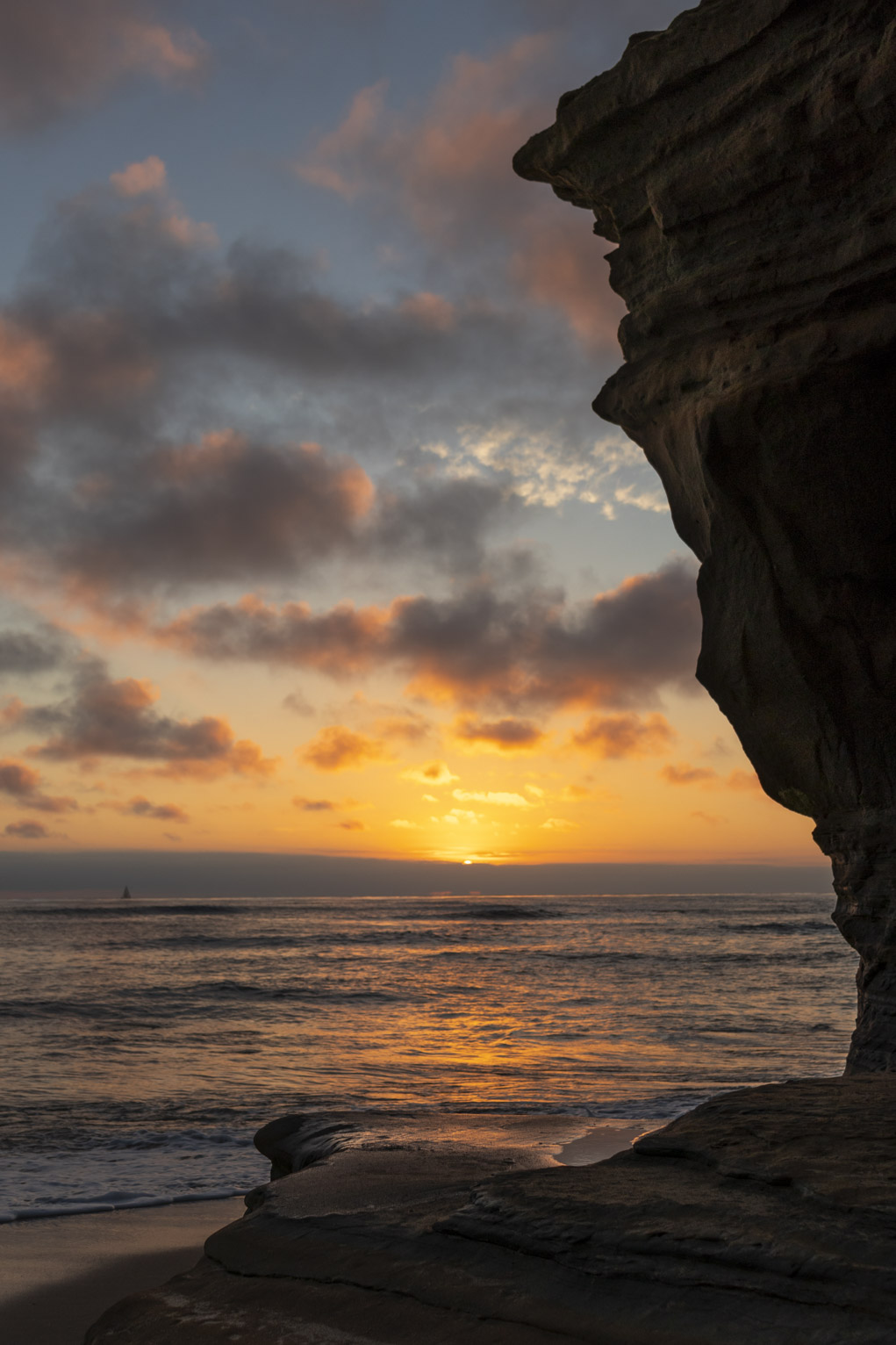 the sun sets lighting the clouds and ocean in orange